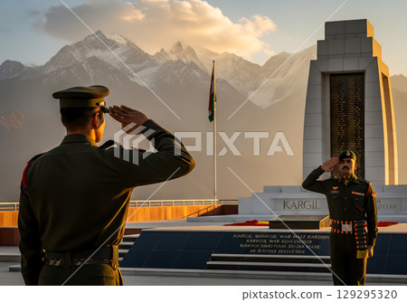 Two Indian soldiers in their 20s, with proud and dedicated expressions, salute a war memorial against a beautiful mountain backdrop at sunset 129295320
