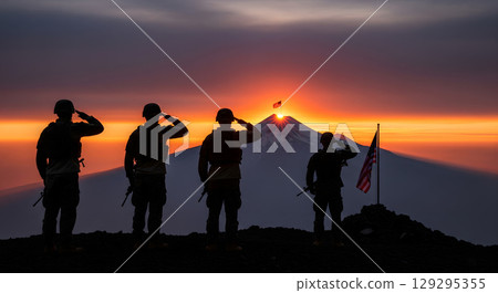A group of four silhouetted soldiers, in their 20s, with proud and solemn expressions, stand on a mountain top saluting as a flag flies at sunset A group of four silhouetted soldiers, in their 20s, with proud and solemn expressions, stand on a mountain top saluting as a flag flies at sunset 129295355