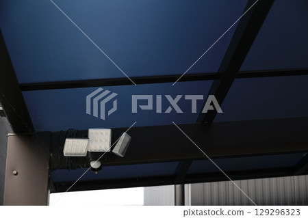 Security sensor light attached to the carport roof 129296323