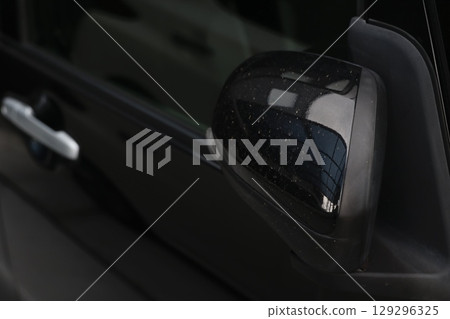 A close-up of white stains on the side mirror of a black car. 129296325