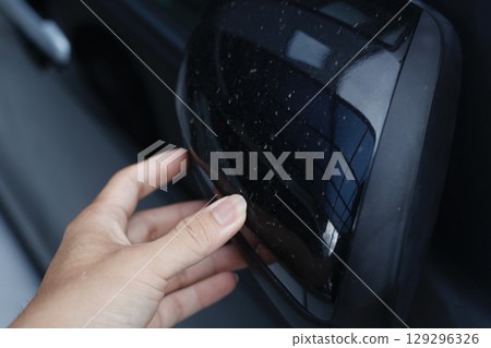 A close-up of white stains on the side mirror of a black car. 129296326