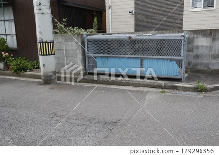 A metal garbage dump installed on the side of a road in a residential area A metal garbage dump installed on the side of a road in a residential area 129296356