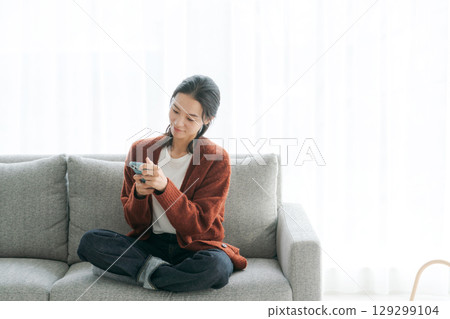 女人在沙發上使用智能手機 129299104