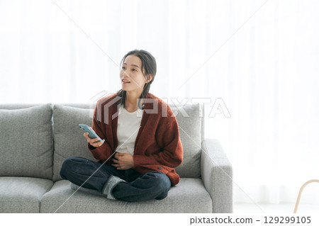 女人在沙發上使用智能手機 129299105