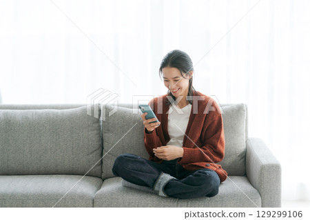 女人在沙發上使用智能手機 129299106