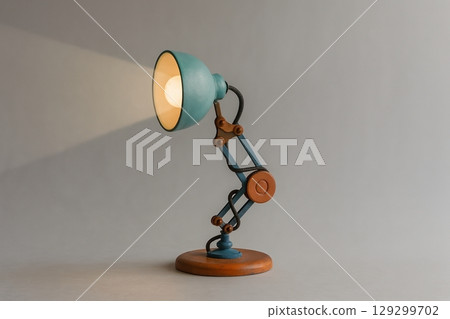 Vintage-style adjustable desk lamp emitting warm light on neutral background 129299702