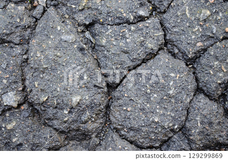 Cracked wet asphalt surface with rough textured road detail 129299869