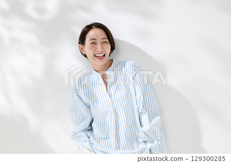 一位微笑的女人站在透過樹梢的陽光下 129300285