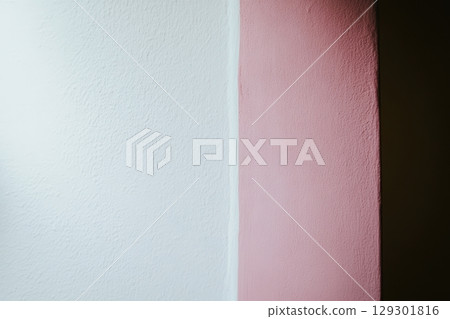Contrast of pastel colors on a wall showcasing white and pink shades in a cozy indoor space 129301816