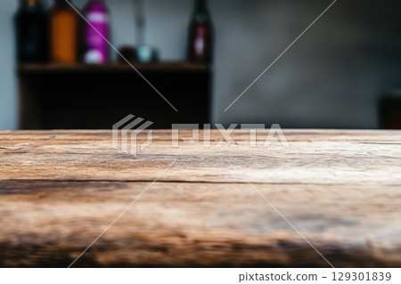 Wooden table close-up with blurred background of colorful bottles in a cozy indoor setting 129301839