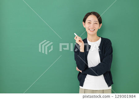 A woman holding a chalk standing in front of a blackboard A woman holding a chalk standing in front of a blackboard 129301984