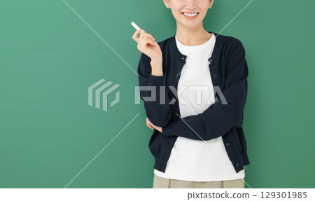 A woman holding a chalk standing in front of a blackboard A woman holding a chalk standing in front of a blackboard 129301985