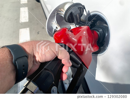 Male Hand Holding Gas Pump Nozzle Pumping Gas Into Vehicle. Male Hand Holding Gas Pump Nozzle Pumping Gas Into Vehicle. 129302080