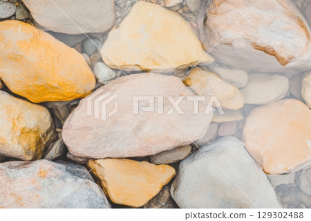 Colorful smooth stones by the river in a tranquil natural setting near sunset 129302488