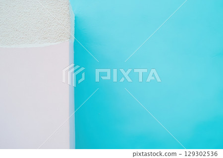 Colorful contrast of pastel pink and vibrant turquoise walls in a sunny outdoor setting 129302536