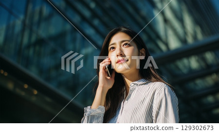 Japanese woman talking on the phone outdoors 129302673