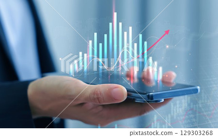 Businessman holding smartphone with glowing stock market chart and upward arrow. Financial growth, investment success, fintech, and trading technology concept. business stock market. Businessman holding smartphone with glowing stock market chart and upward arrow. Financial growth, investment success, fintech, and trading technology concept. business stock market. 129303268