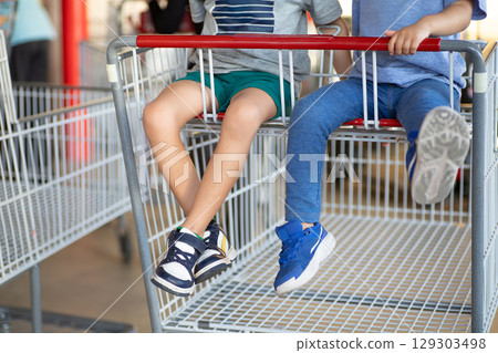 Children riding in large shopping carts 129303498