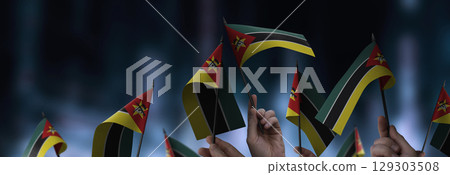Mozambique flags in their hands on a blurred urban background Mozambique flags in their hands on a blurred urban background 129303508