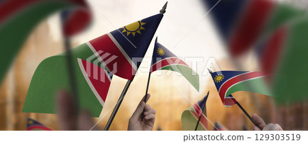 Namibia flags in their hands on a blurred urban background Namibia flags in their hands on a blurred urban background 129303519