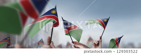 Namibia flags in their hands on a blurred urban background 129303522