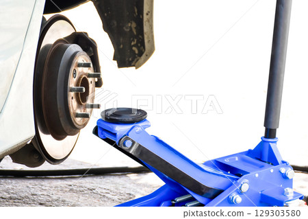 Jack lifting a car, car repair, vehicle maintenance, tire change 129303580