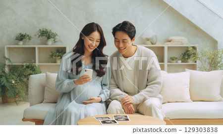 A woman in a dress smiles as she looks at a photo of her unborn child 129303838