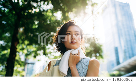 A woman wipes her neck in a green space in summer 129303862