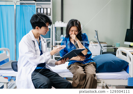 Doctor discussing treatment with male patient talks to discuss results or symptoms and sitting on examination desk 129304111