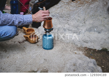 Person Preparing Outdoor Coffee on Portable Stove During Camping Adventure Person Preparing Outdoor Coffee on Portable Stove During Camping Adventure 129304189