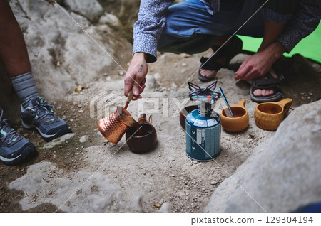 Camping Scene with Copper Pot and Outdoor Cookware in Rustic Mountain Setting Camping Scene with Copper Pot and Outdoor Cookware in Rustic Mountain Setting 129304194