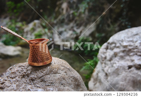 Traditional Copper Coffee Pot on Rock in Natural Outdoor Setting Traditional Copper Coffee Pot on Rock in Natural Outdoor Setting 129304216