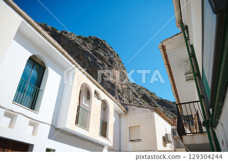 Traditional Mediterranean Town Scene with Whitewashed Walls and Mountain Backdrop on a Clear Day Traditional Mediterranean Town Scene with Whitewashed Walls and Mountain Backdrop on a Clear Day 129304244