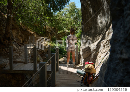 Woman Exploring a Scenic Tree-Shaded Trail with Backpack and Gear 129304256