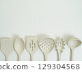 Set of beige silicone kitchen utensils neatly arranged in a row on a white background 129304568