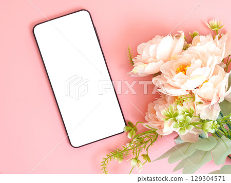 Smartphone with blank white screen placed on pink background beside pastel flowers. Smartphone with blank white screen placed on pink background beside pastel flowers. 129304571