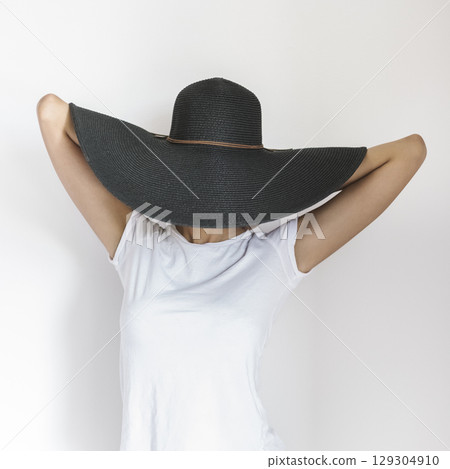 Woman Wearing Large Black Hat with Arms Behind Head 129304910
