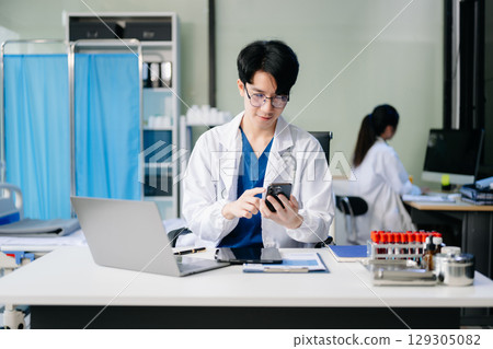 Doctor analyzing patient data on tablet in clinical lab. Medical professional in hospital with laptop, blood samples Doctor analyzing patient data on tablet in clinical lab. Medical professional in hospital with laptop, blood samples 129305082