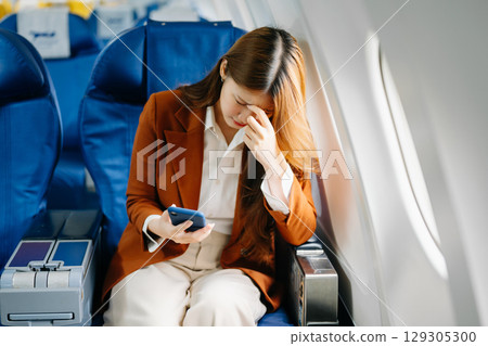 Young Asian executive excels in first class, multitasking with digital tablet, laptop and smartphone Young Asian executive excels in first class, multitasking with digital tablet, laptop and smartphone 129305300
