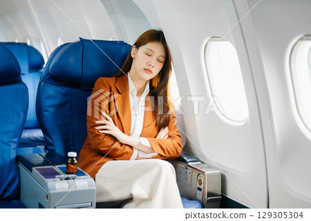 Photo of a frustrated woman sitting on an airplane with her head in her hands 129305304