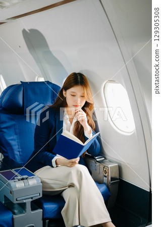 Young Asian executive excels in first class, multitasking with digital tablet, laptop and smartphone 129305308