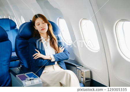 Photo of a frustrated woman sitting on an airplane with her head in her hands 129305335