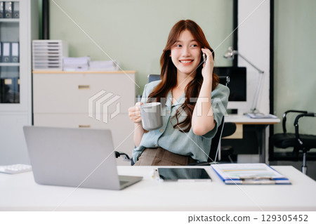 Confident Asian woman with a smile standing holding notepad and tablet Confident Asian woman with a smile standing holding notepad and tablet 129305452