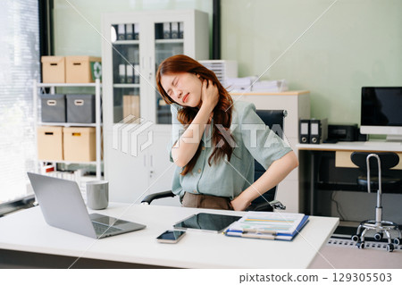 Overworked young Asian businesswoman office worker suffering from neck pain after had a long da Overworked young Asian businesswoman office worker suffering from neck pain after had a long da 129305503