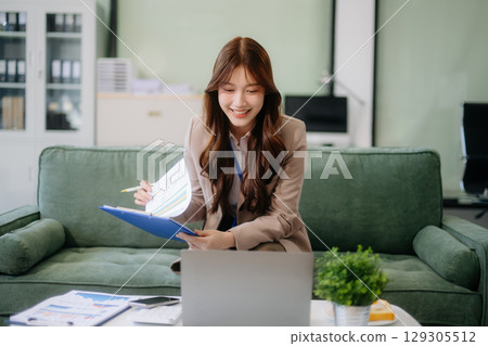 Asian businesswomen brainstorming in a cozy office, collaborating with a laptop and notebook. Perfect for teamwork Asian businesswomen brainstorming in a cozy office, collaborating with a laptop and notebook. Perfect for teamwork 129305512