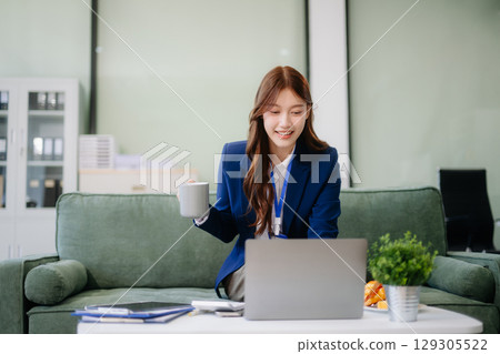 Asian businesswomen brainstorming in a cozy office, collaborating with a laptop and notebook. Perfect for teamwork Asian businesswomen brainstorming in a cozy office, collaborating with a laptop and notebook. Perfect for teamwork 129305522