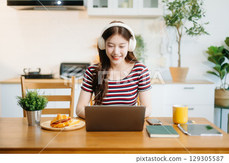 oung Asian woman with sitting working on laptops and tablets in a cozy workspace. Perfect for education, innovation, oung Asian woman with sitting working on laptops and tablets in a cozy workspace. Perfect for education, innovation, 129305587