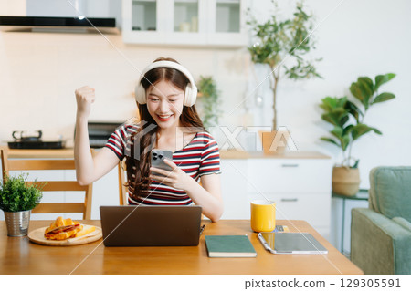 oung Asian woman with sitting working on laptops and tablets in a cozy workspace. Perfect for education, innovation, oung Asian woman with sitting working on laptops and tablets in a cozy workspace. Perfect for education, innovation, 129305591