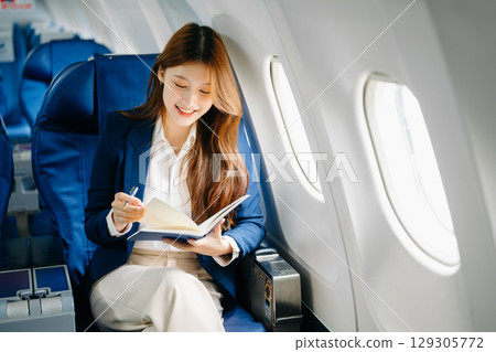 Young Asian executive excels in first class, multitasking with digital tablet, laptop and smartphone 129305772