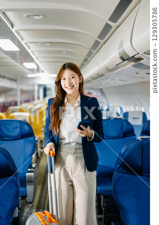 Asian female passenger of airplane sitting in comfortable seat while working laptop and tablet. Travel in style, Asian female passenger of airplane sitting in comfortable seat while working laptop and tablet. Travel in style, 129305786